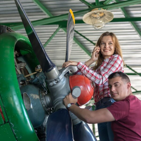 two people working on a farming plane propeller